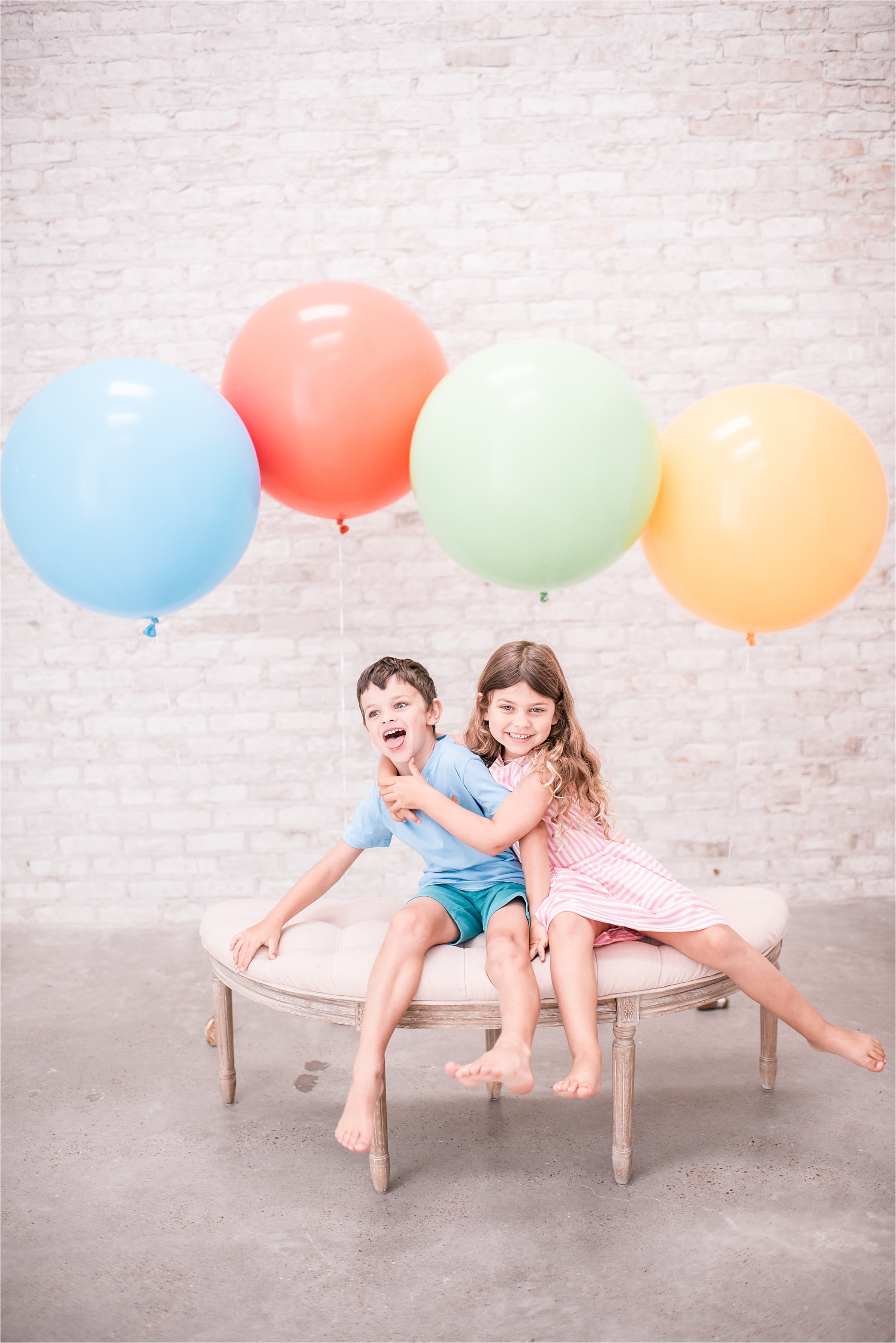 kids being kids during a studio portrait session. white brick and giant helium balloons.