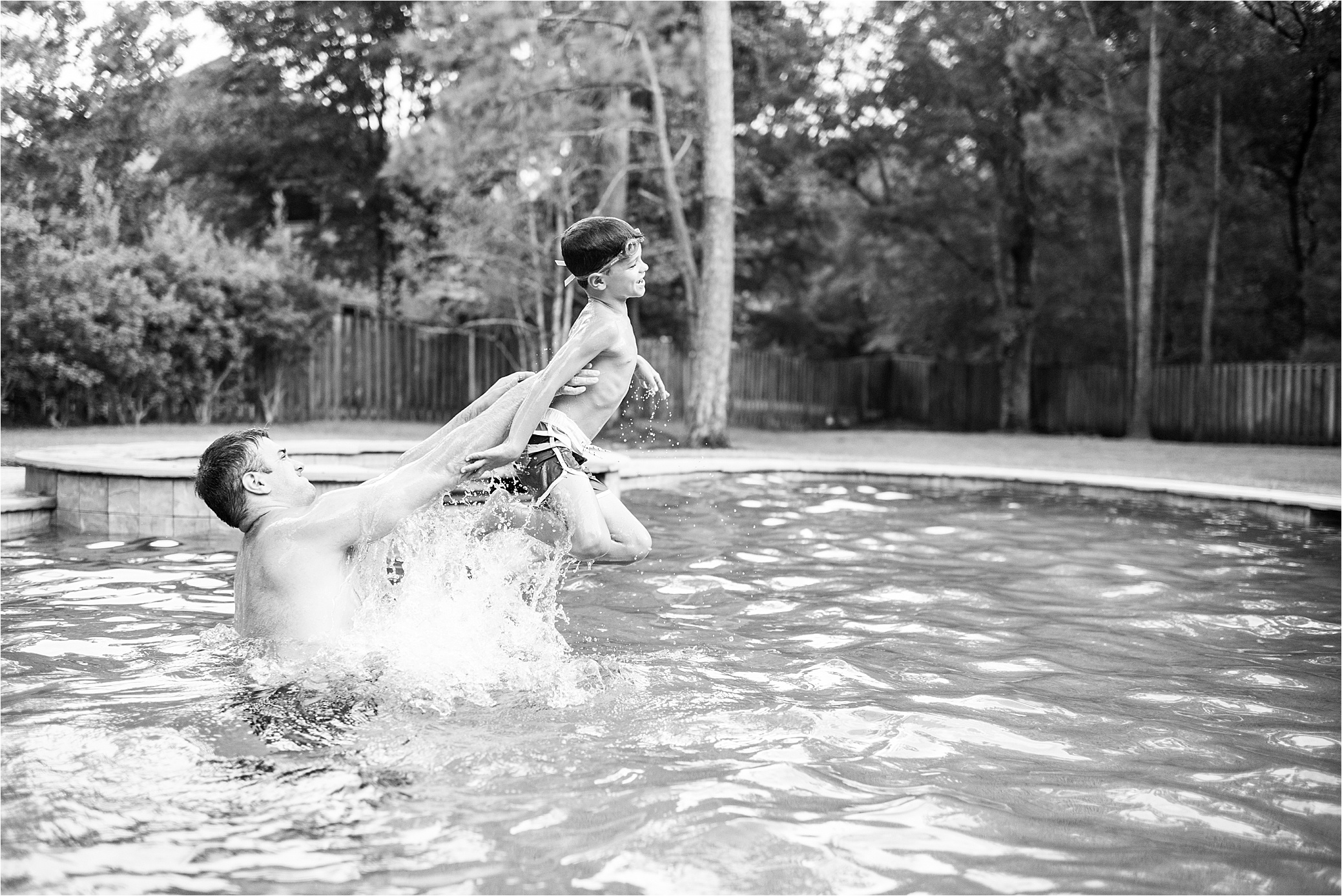 image of dad tossing son up in air, pool photo. black and white.