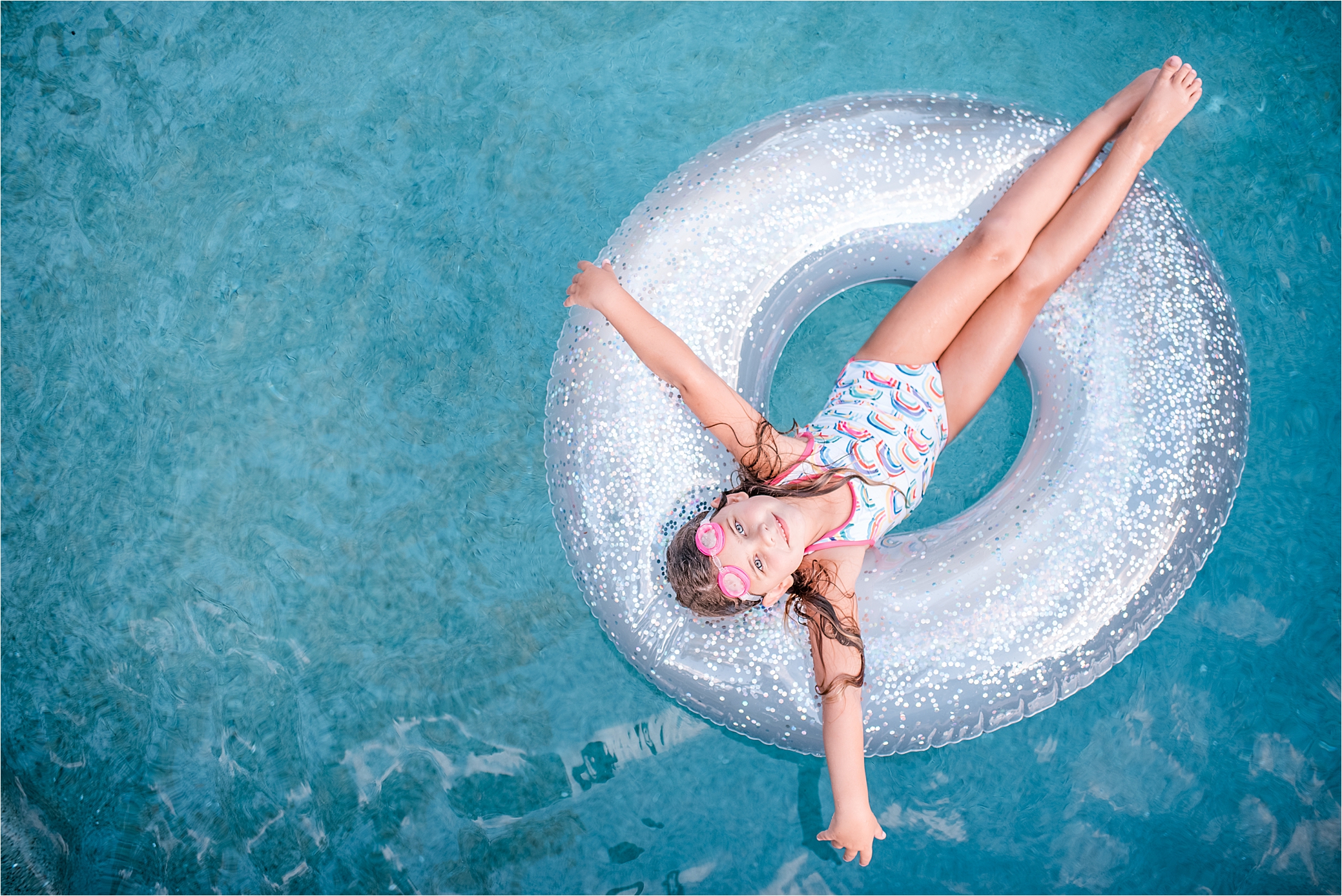 girl on sparkle float in the middle of the pool.