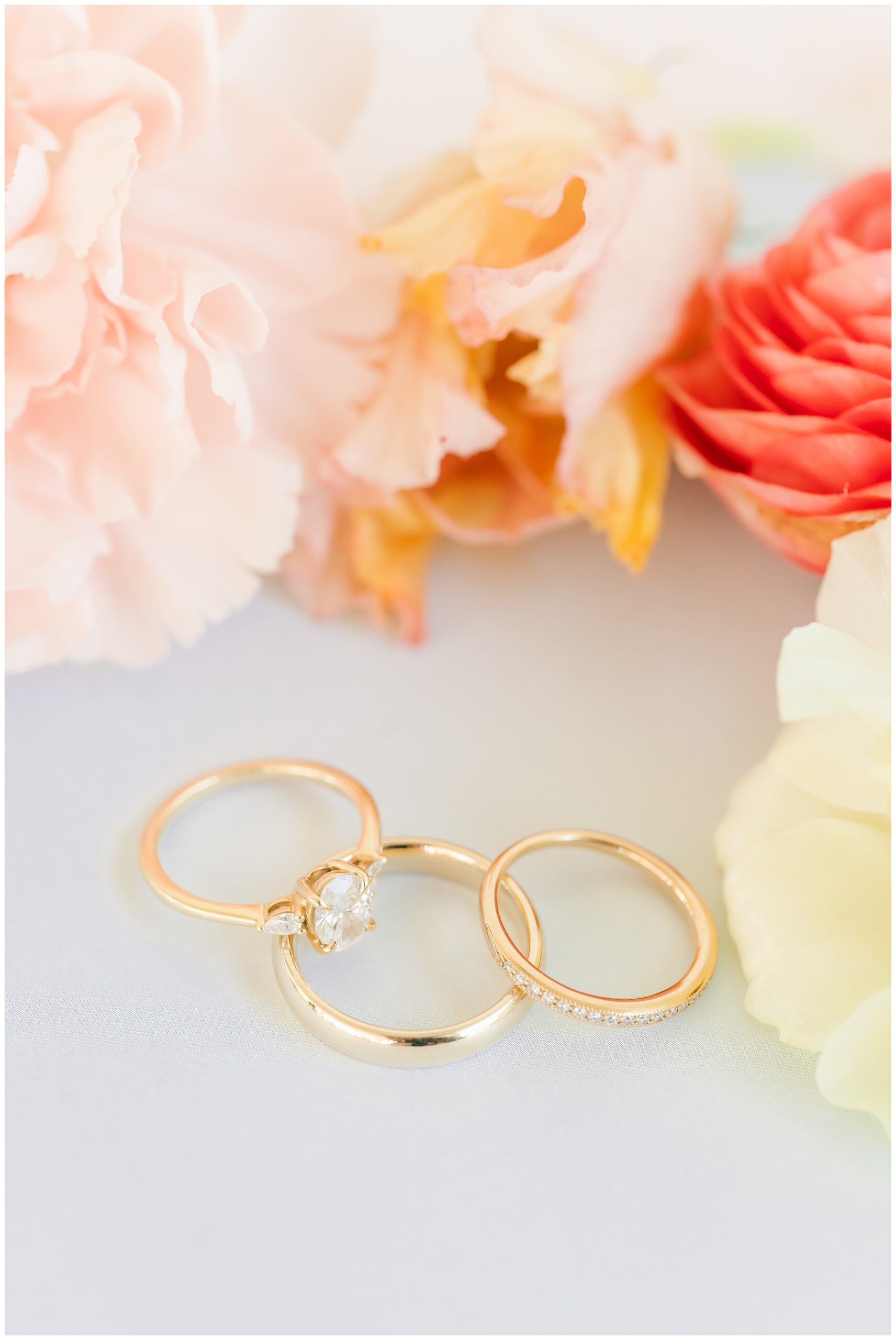 detail photo of gold wedding bands on coral flowers.