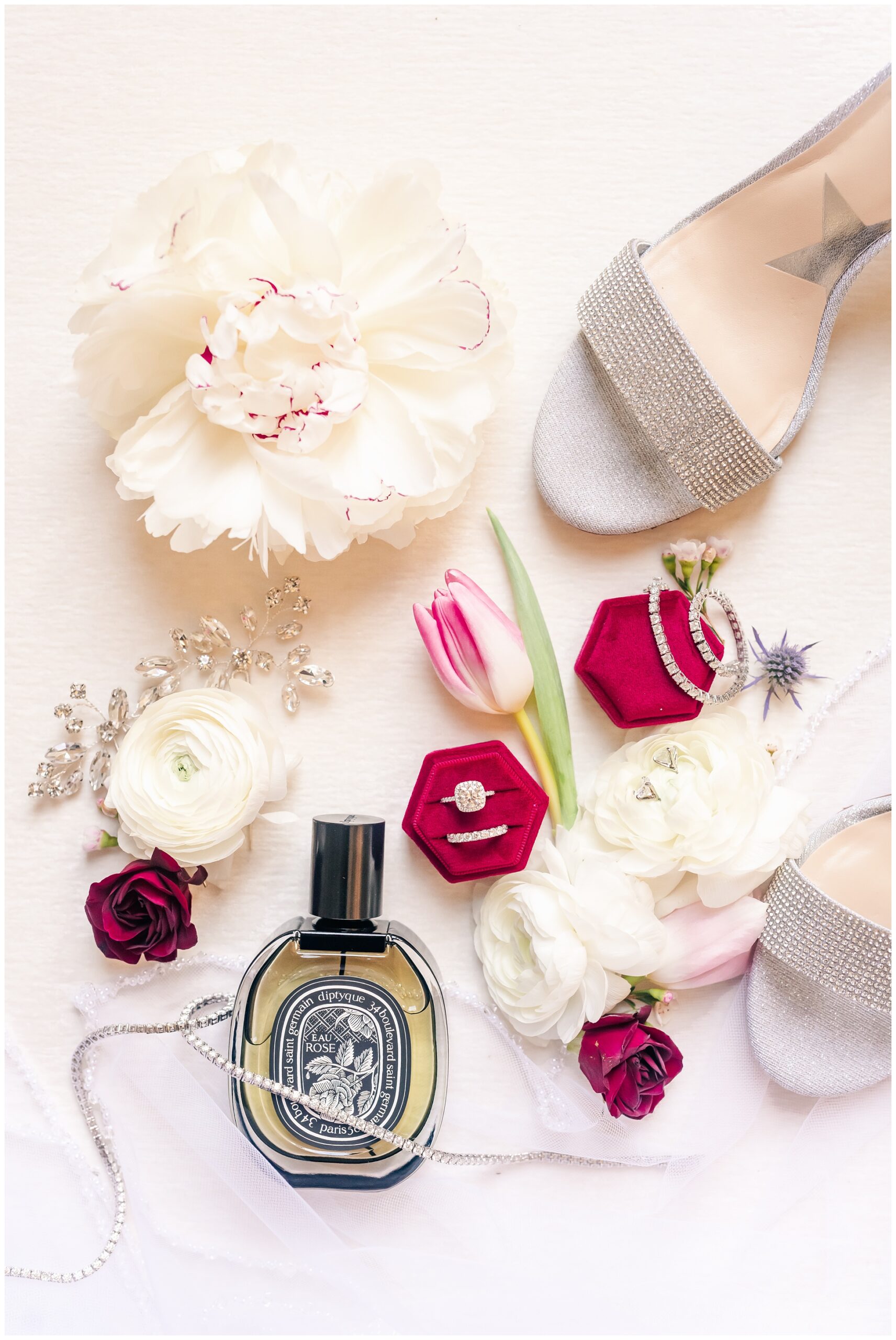 Bridal details flatlay featuring diptych perfume paris, jewelry, shoes, florals.