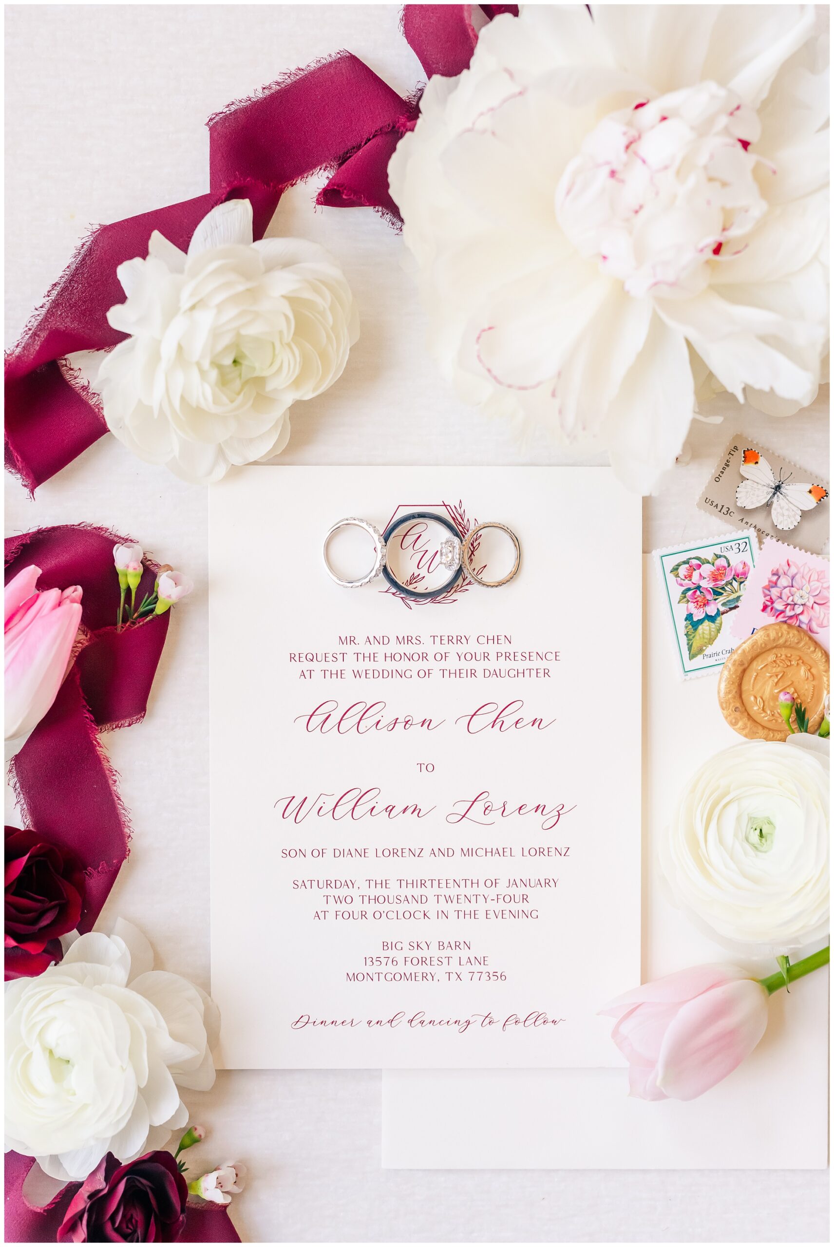 Wedding Invitation flatlay with florals, stamps, wax seal and wedding rings.