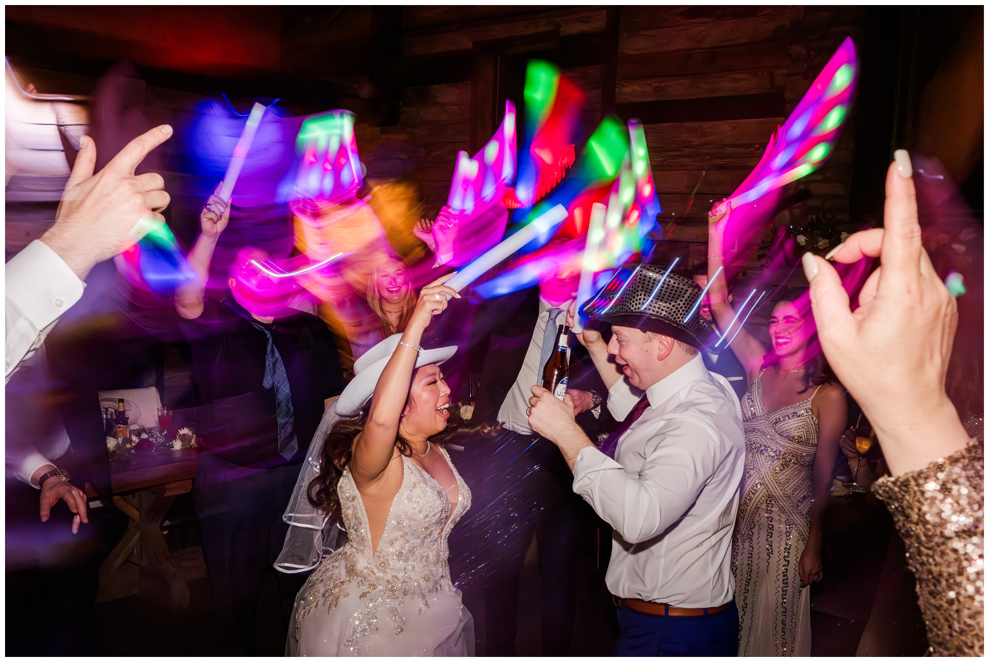 lights and color swirl around dancing bride and groom with hats during wedding reception at Big Sky Barn.