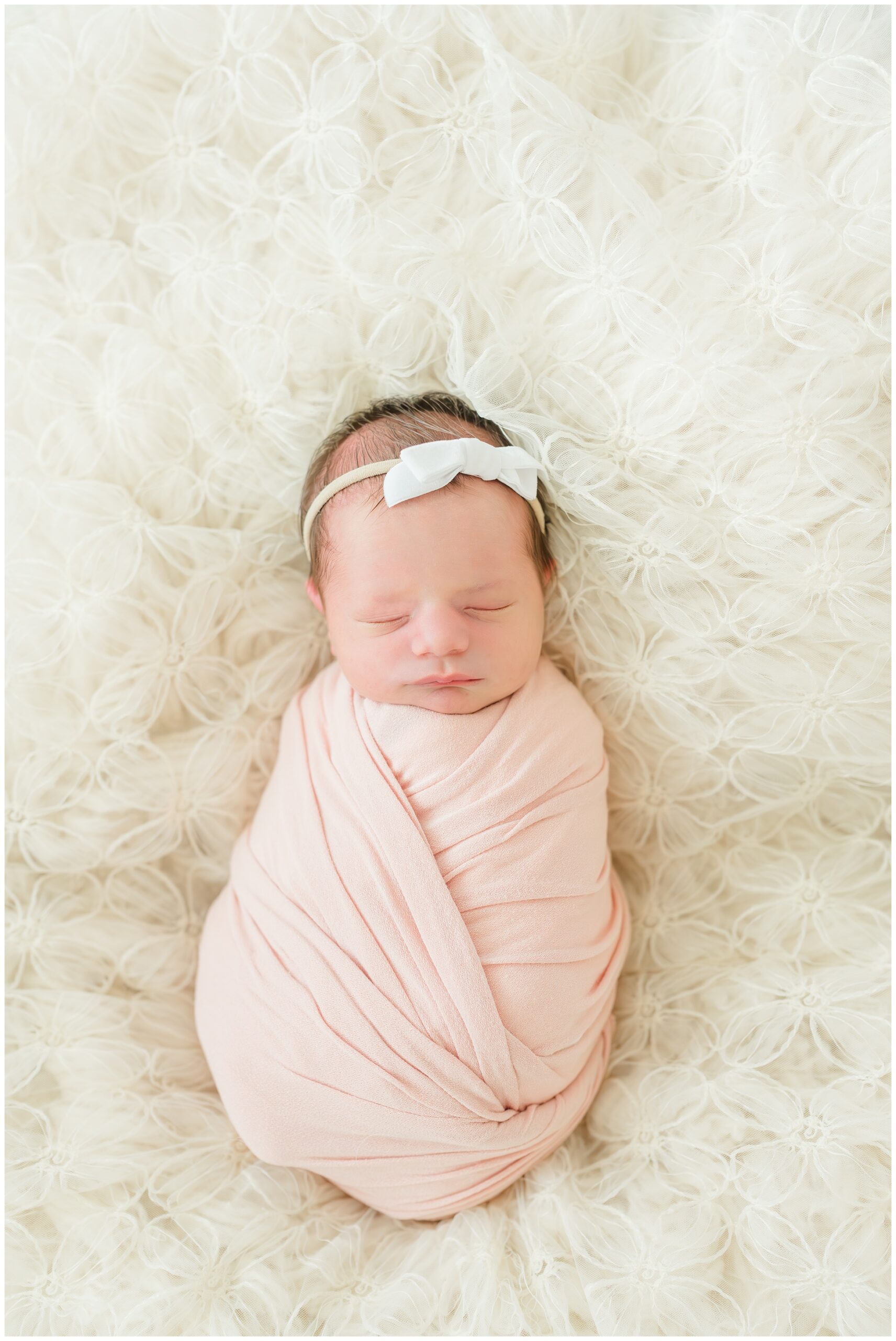 Newborn Photography in The Woodlands, baby wrapped in pink with a white bow. 