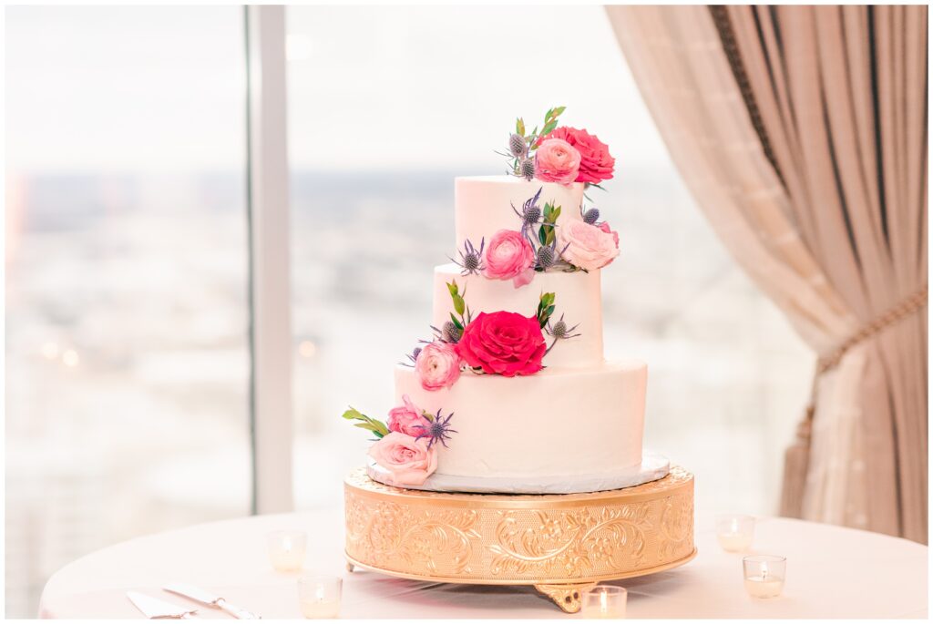 Wedding Cake with pink flowers n front of window in the Petroleum Club overlooking downtown Houston.
